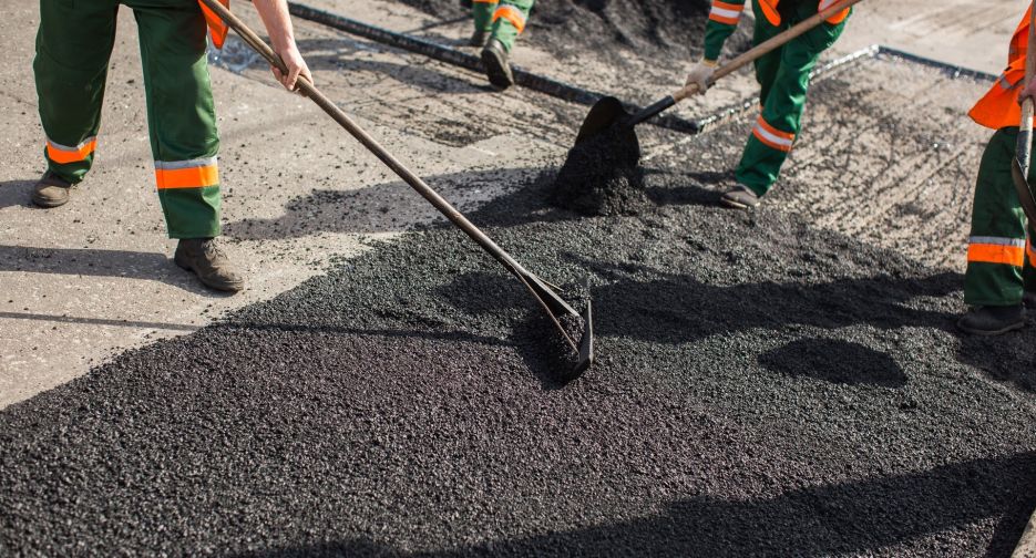 Builder during Asphalting road works level raw material before the operation of the machine